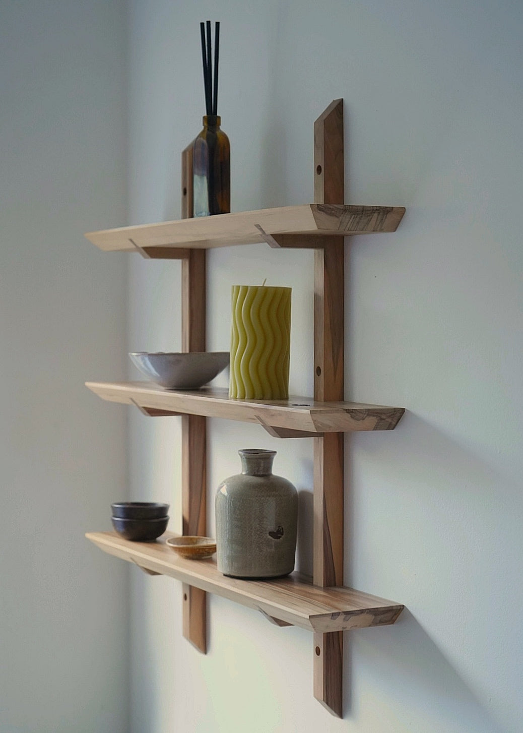 Wooden wall shelves with decorative items against a plain wall.