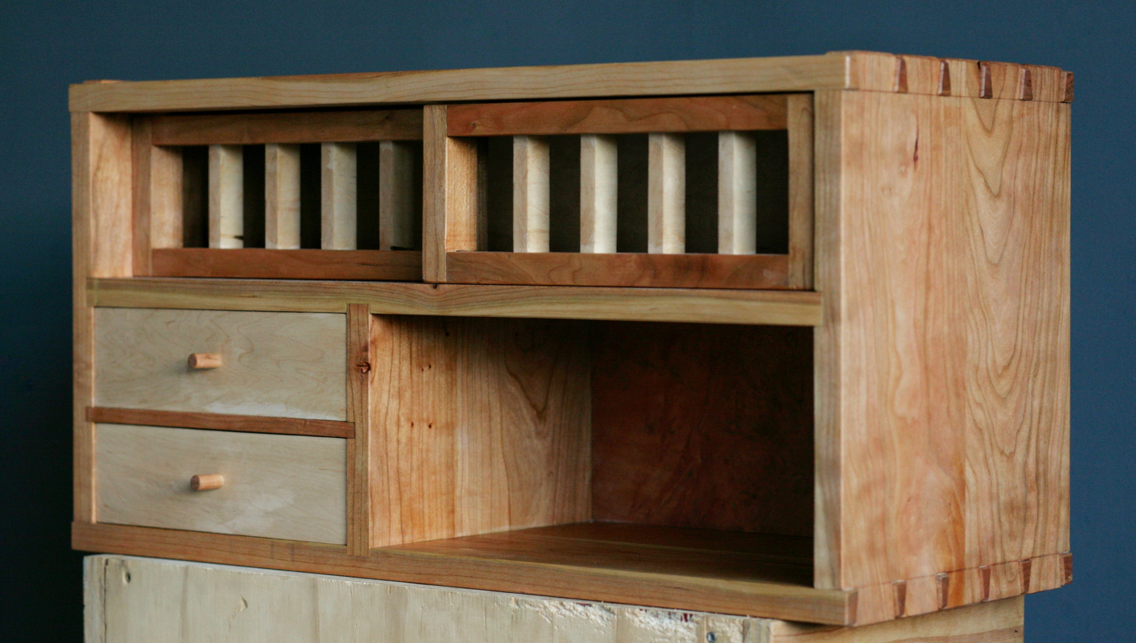 Wooden cabinet with drawers and shelves against a dark background.