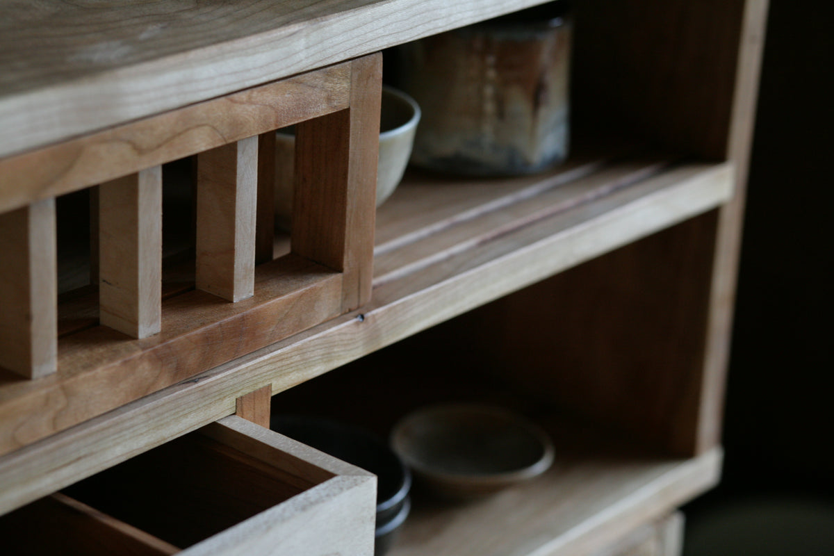 Wooden shelf with ceramic bowls and cups on display.