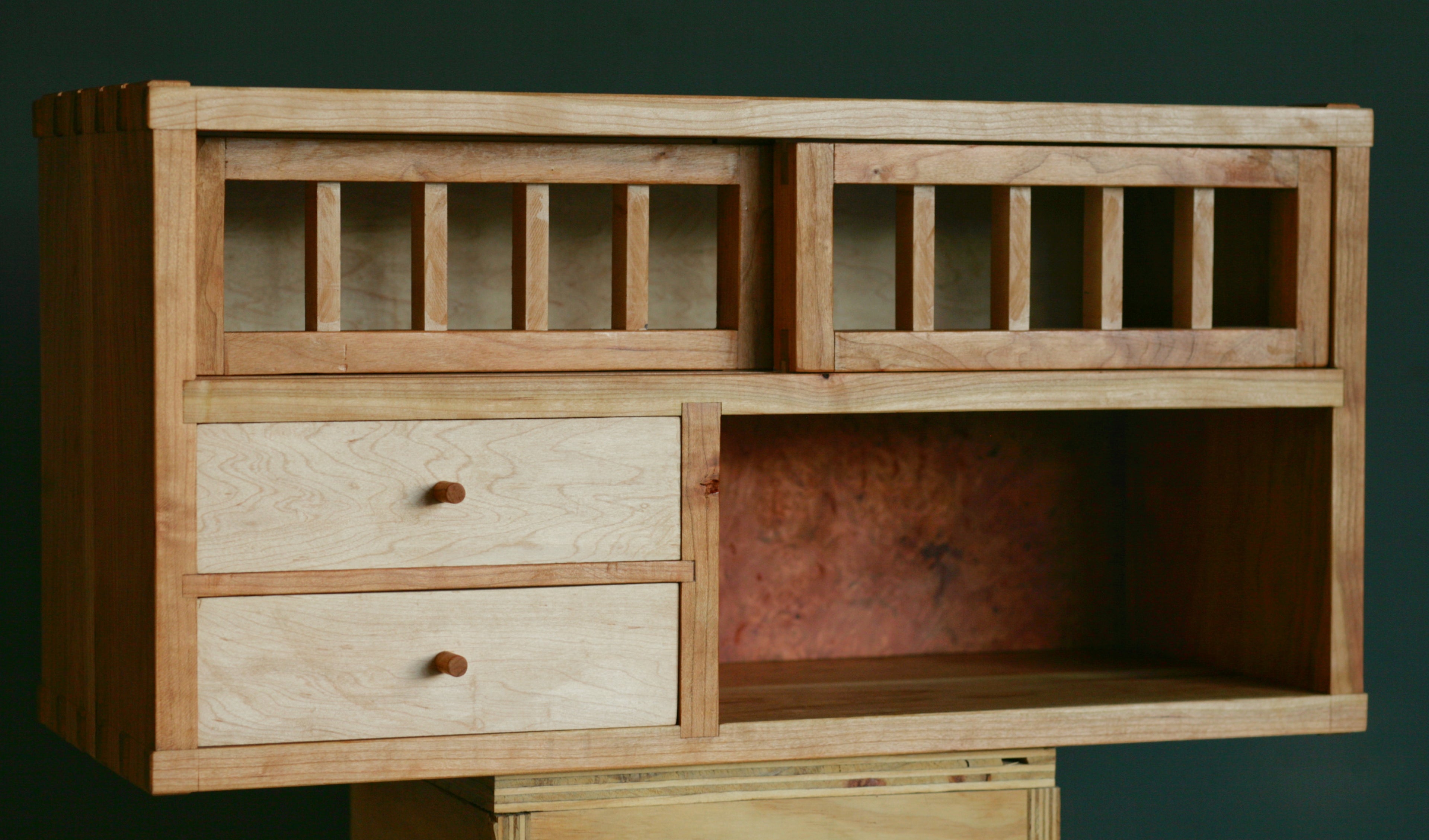 Wooden cabinet with drawers and open shelves on a dark background.